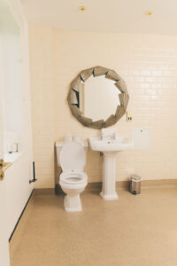 bathroom with circle mirror and toilet