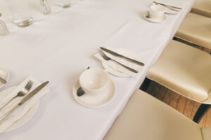 dining table with cup and plate sets next to knife and forks